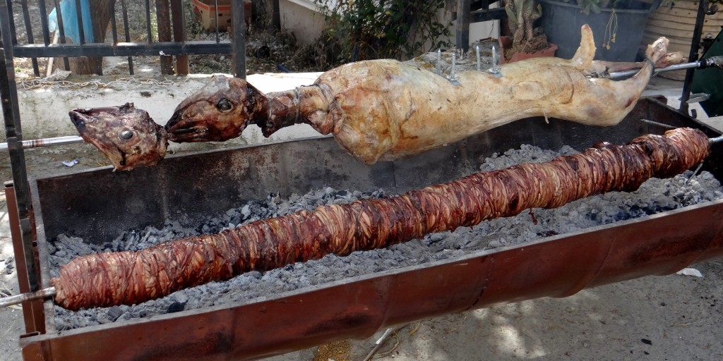 Roasting lamb, next to it is it's intestines wrapped around another spit!