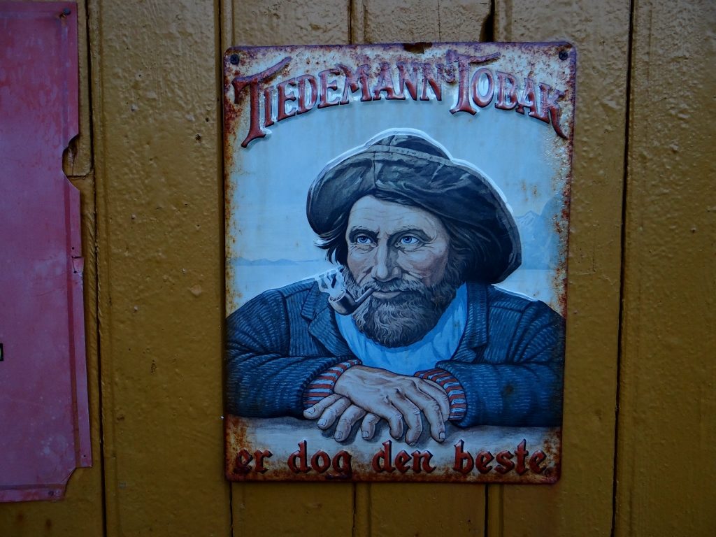 Old ad for tobacco on ye-olde general store (closed but we could see the wild-west look of the supplies on wooden shelves through the window) in Nusfjord