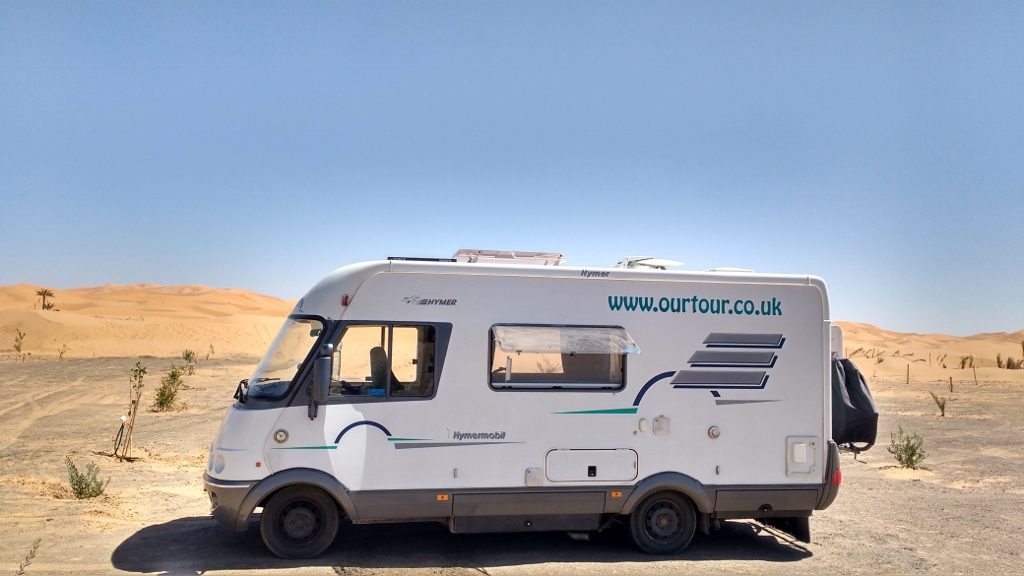 Motorhome by the sand dunes of Erg Chebbi on the pre-Saharan Steppe in Morocco