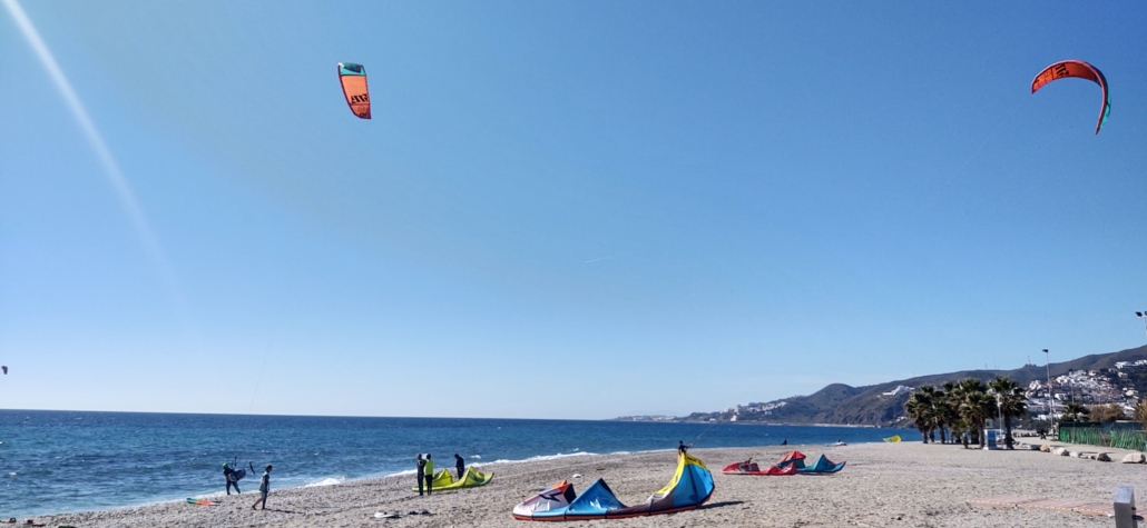 Colourful kit surfers on Playa Playazo in Nerja, a short walk from the campsite