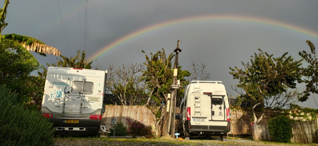 Double rainbow over two motorhomes campervans in Nerja campsite in Spain on a cloudy day