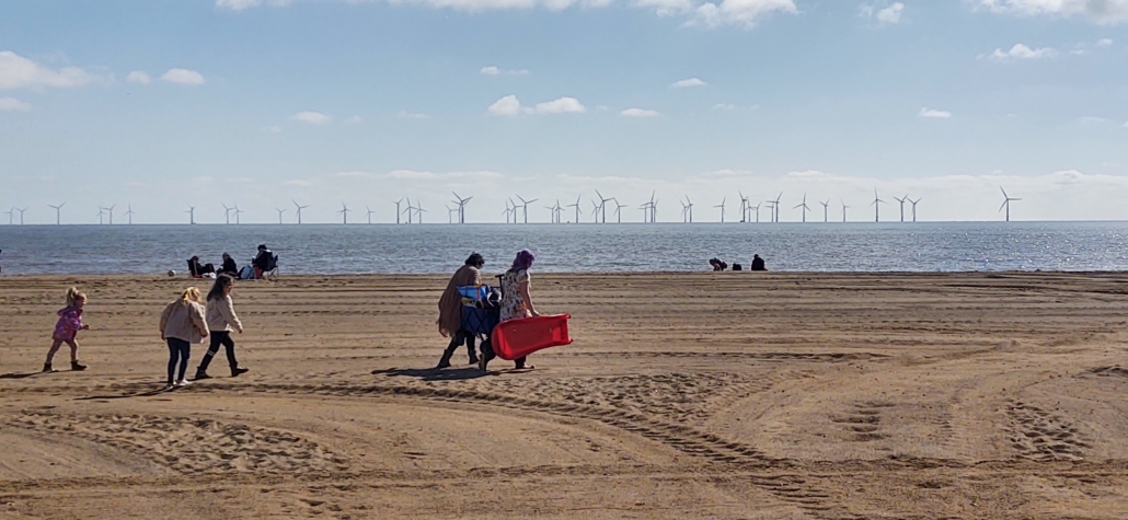 Families on the beach with the offshore windfarms at Skegness in the background.