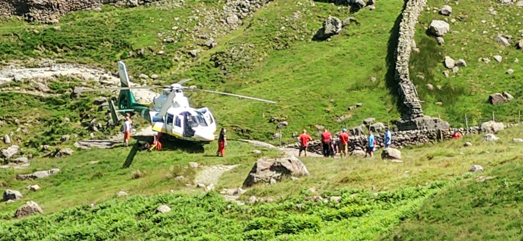Mountain rescue team and a helicopter taking an injured hiker to hospital south of Seathwaite Farm