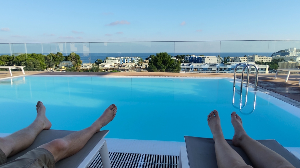 Feet on a sunlounger at a roof top pool