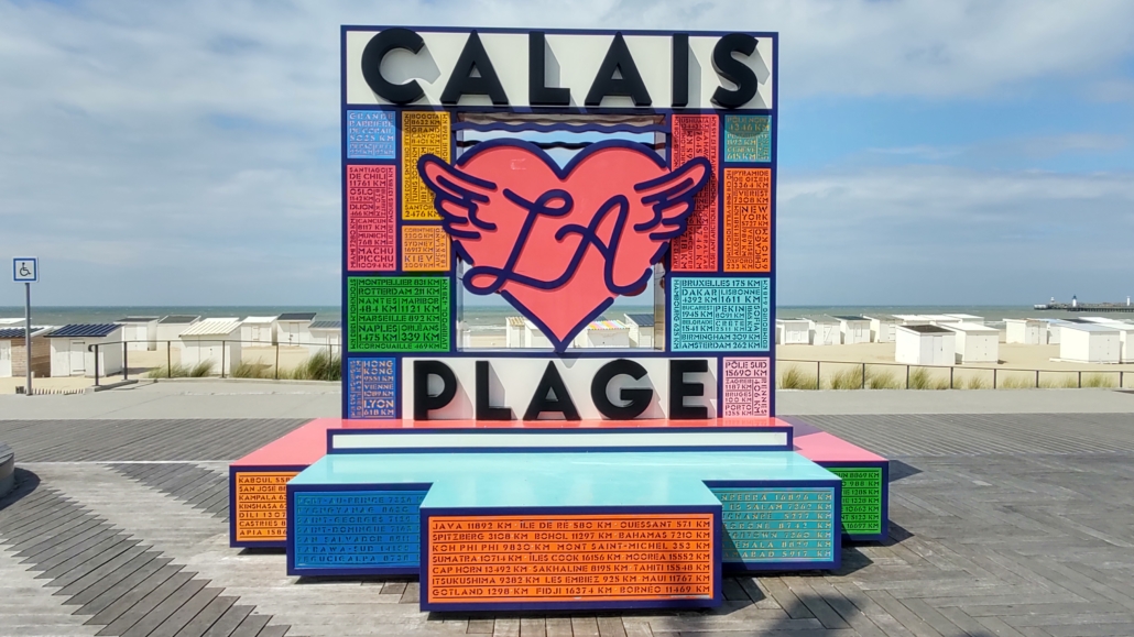 The Calais Plage colourful sign with distances to places across the planet