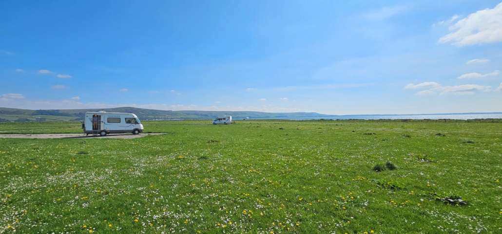 view of two motorhomes parked miles apart in a field