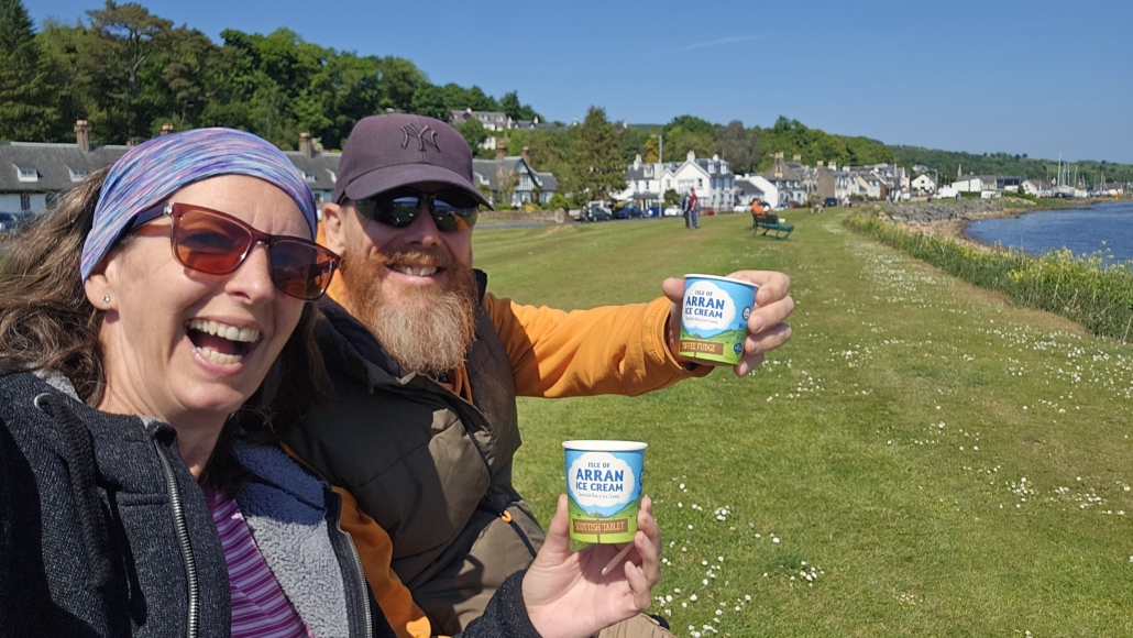 Both of us sat on a bench by the sea with mini tubs of ice cream