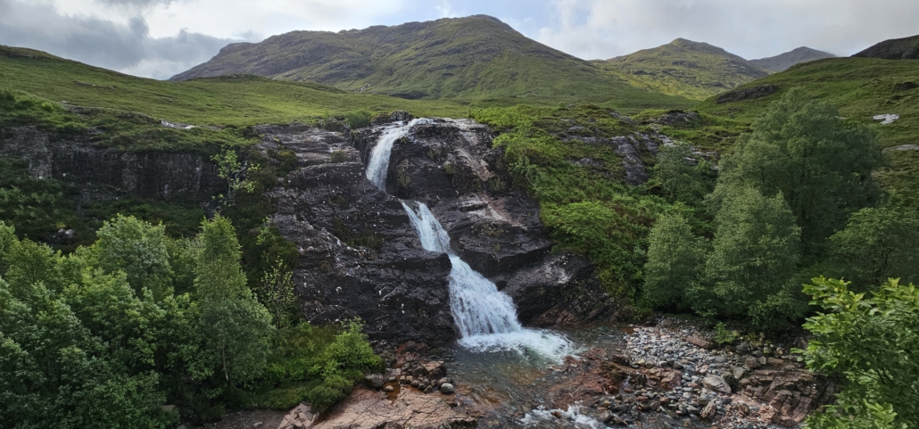Waterfall surrounded by green mountains