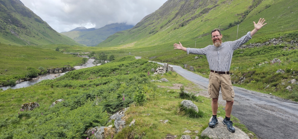 Jay stood on a rock with valley and mountain behind him