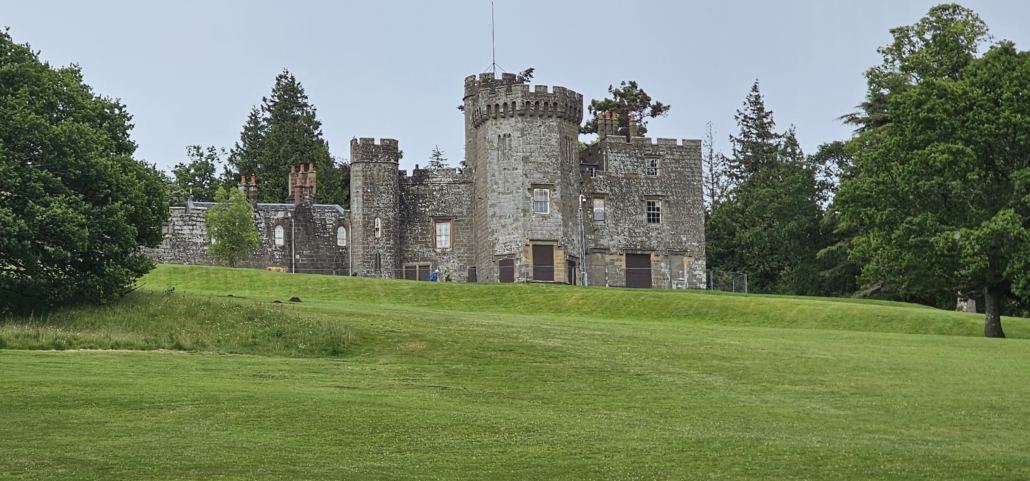 Stone castle surrounded by trees on a green lawn