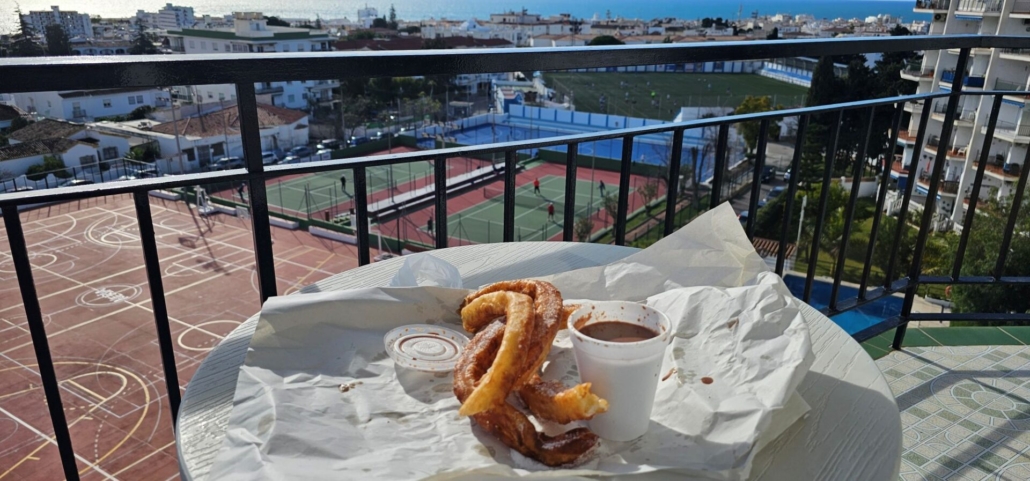 Spanish churros and chocolate on a balcony with a view of the sea